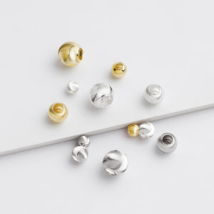 A collection of gold-plated cat's eye spacer beads in various sizes laid out on a white surface.